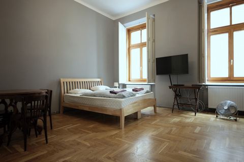 This spacious 2-bedroom apartment for rent on Klauzál tér is on the 1st floor. It’s a rather unique space. The front door opens into the big, fully-equipped kitchen. This area is tiled, and from here you have access to the toilet and the bathroom. Bo...